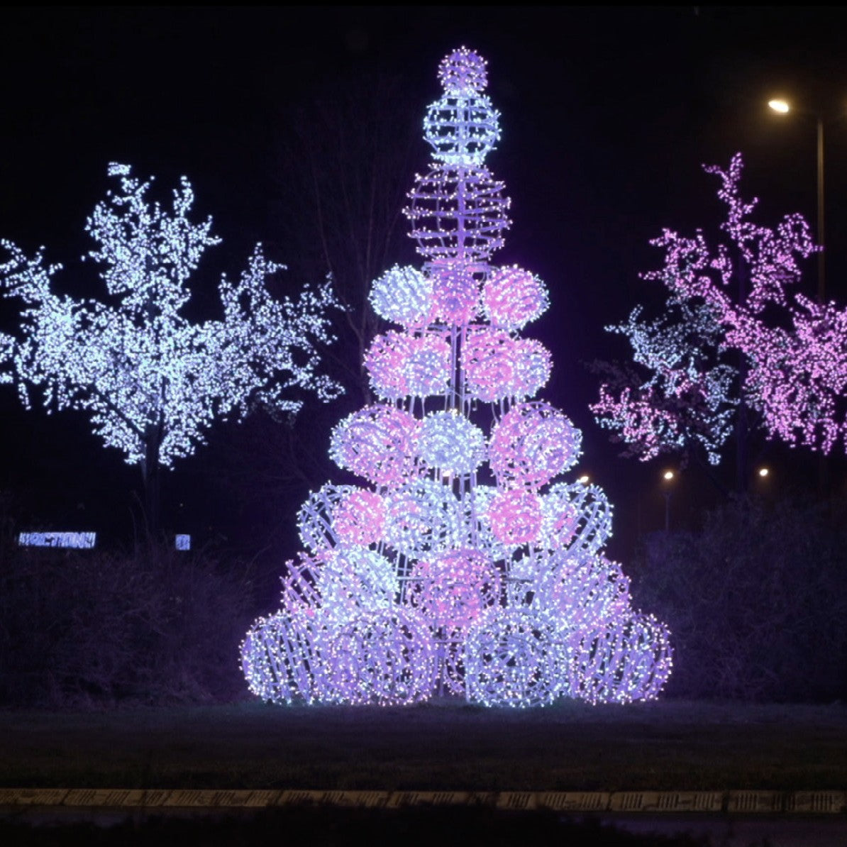 Pyramide boules en situation sur un rond-point, de nuit, ici en rose, entre deux arbres lumineux (non compris)
