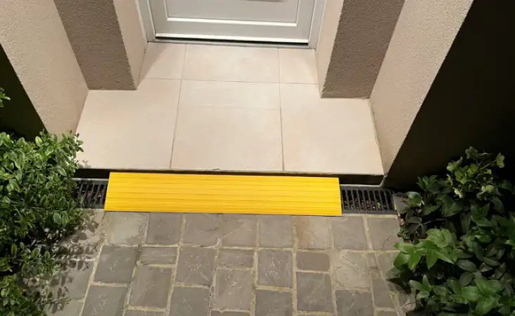 Rampe de seuil jaune posée devant une porte d'entrée