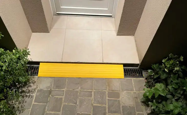 Rampe de seuil jaune posée devant une porte d'entrée